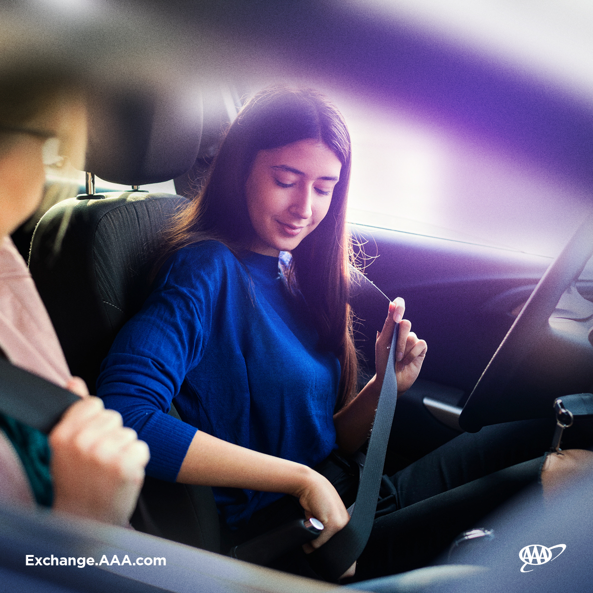 A teen driver buckles her seatbelt.