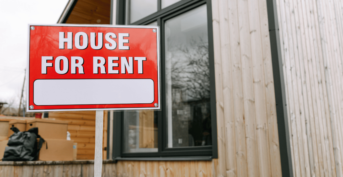 A photo of a house with a "House for rent" sign in the front yard.