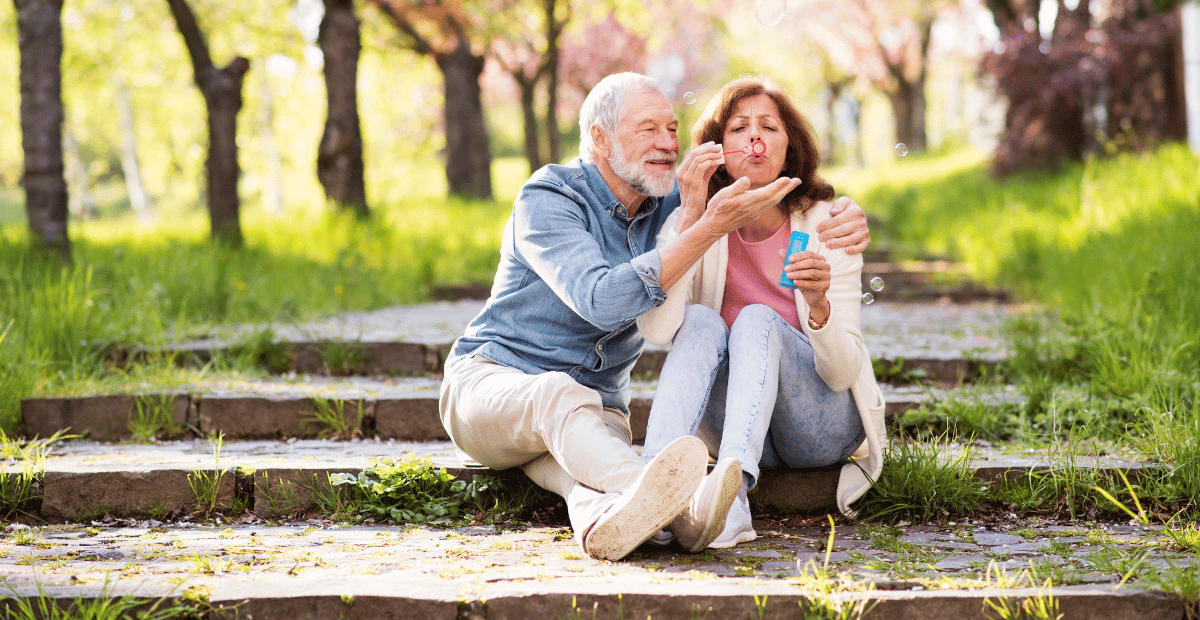A man and woman sit in a park and play with bubbles