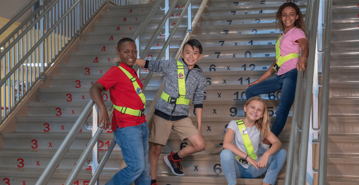 Four student members of the AAA Safety Patrol pose wearing their safety patrol belts